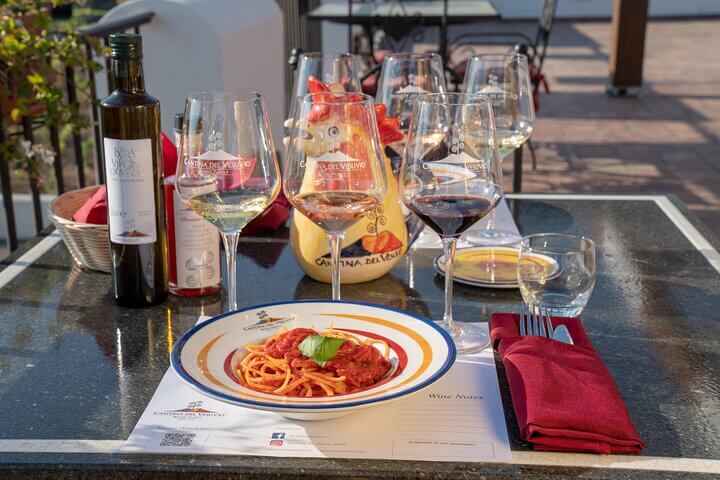 Tourists enjoying pompeii food indoors.Served plates of pasta on a table with white wine.